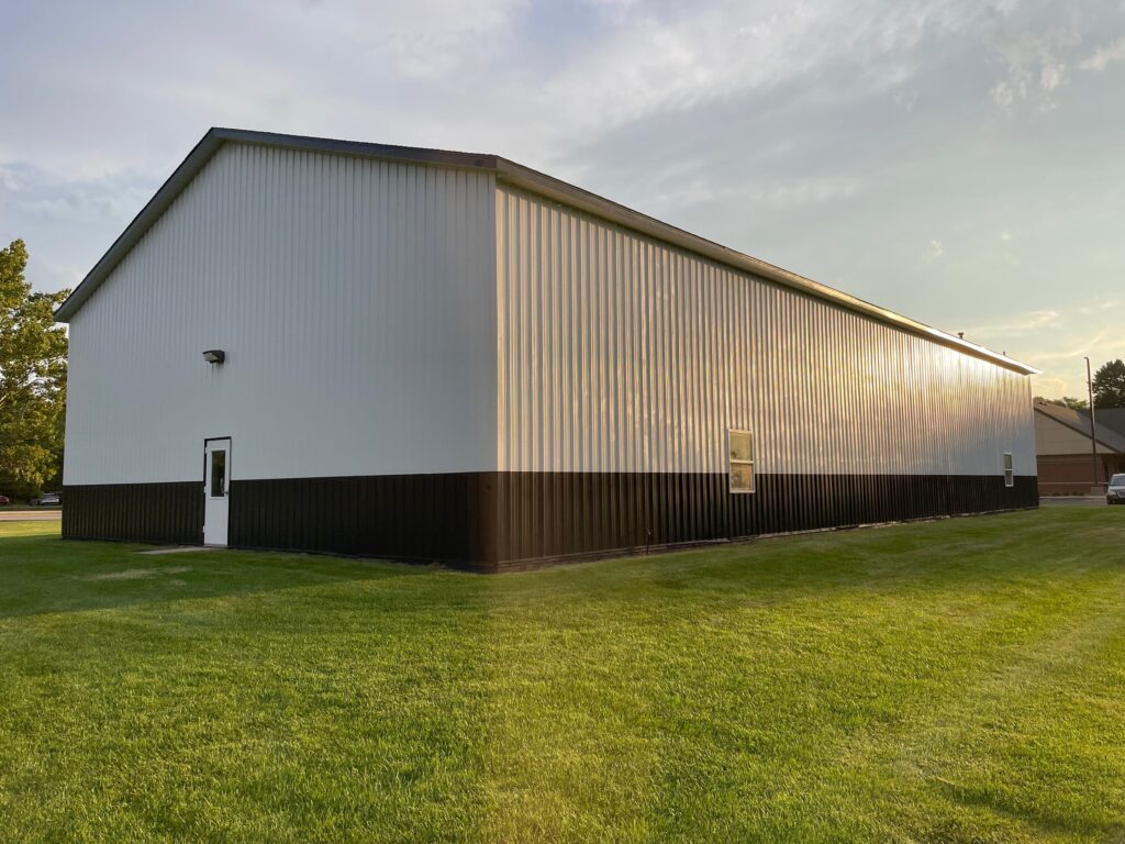 Finished exterior painting on the West Ottawa maintenance barn with white siding on top and black siding on the bottom.