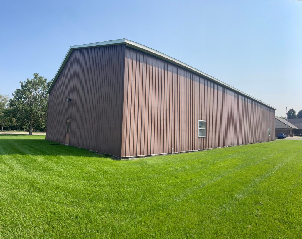 Finished exterior painting on the West Ottawa maintenance barn with white siding on top and black siding on the bottom.