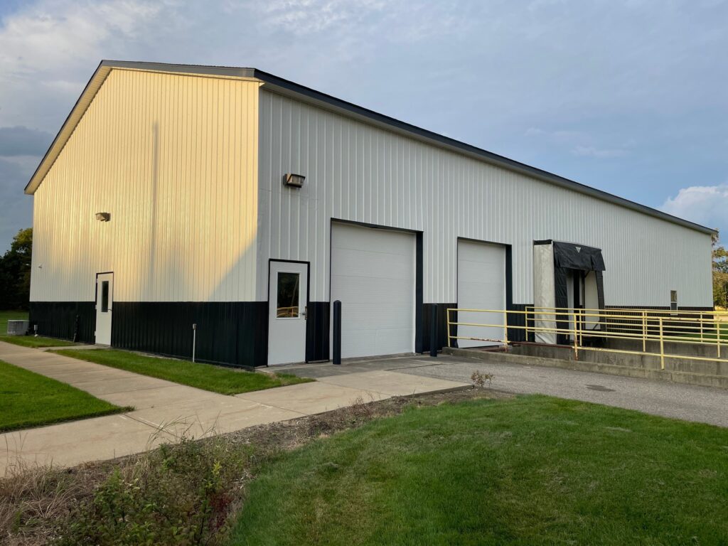 Finished exterior painting on the West Ottawa maintenance barn with white siding on top and black siding on the bottom.