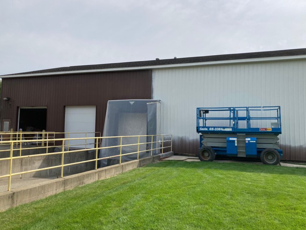 Finished exterior painting on the West Ottawa maintenance barn with white siding on top and black siding on the bottom.