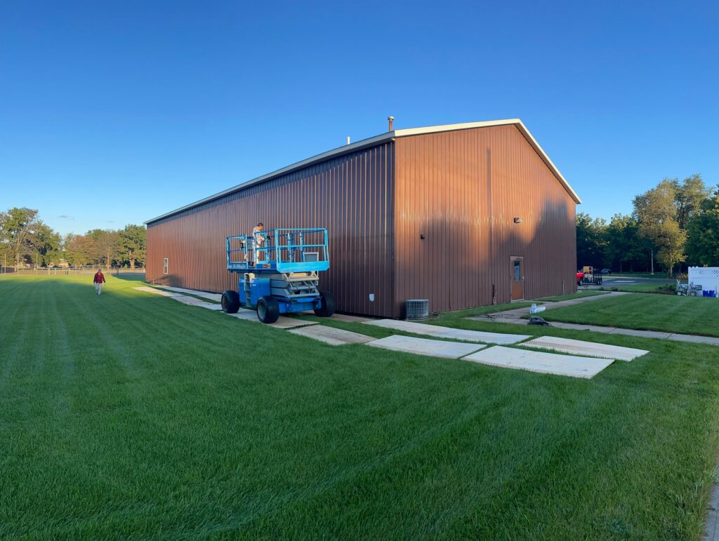 Finished exterior painting on the West Ottawa maintenance barn with white siding on top and black siding on the bottom.