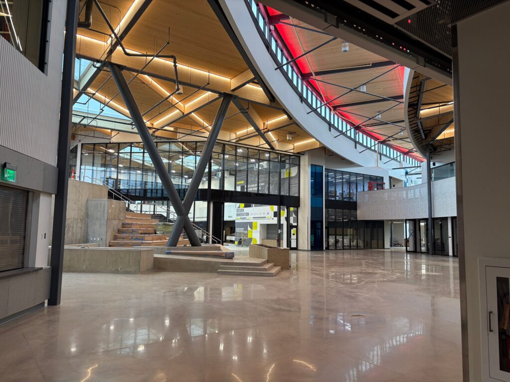 Polished concrete floor in modern commercial atrium with black steel structural trusses and warm LED ceiling lighting.