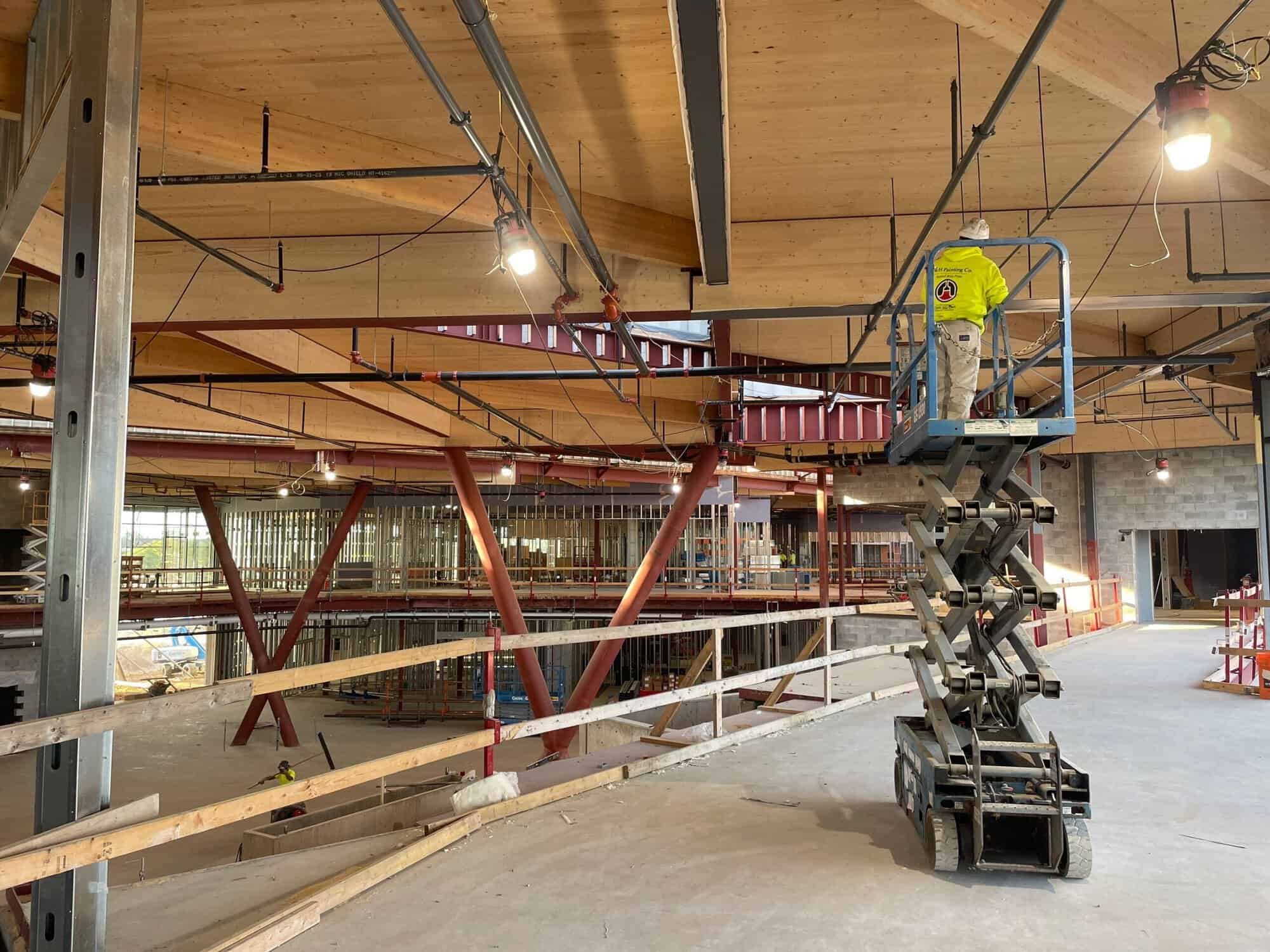Second Floor Corridor 2 H&H Painting crew member on a scissor lift below protected mass timber decking during the KRESA Career Connect Campus project
