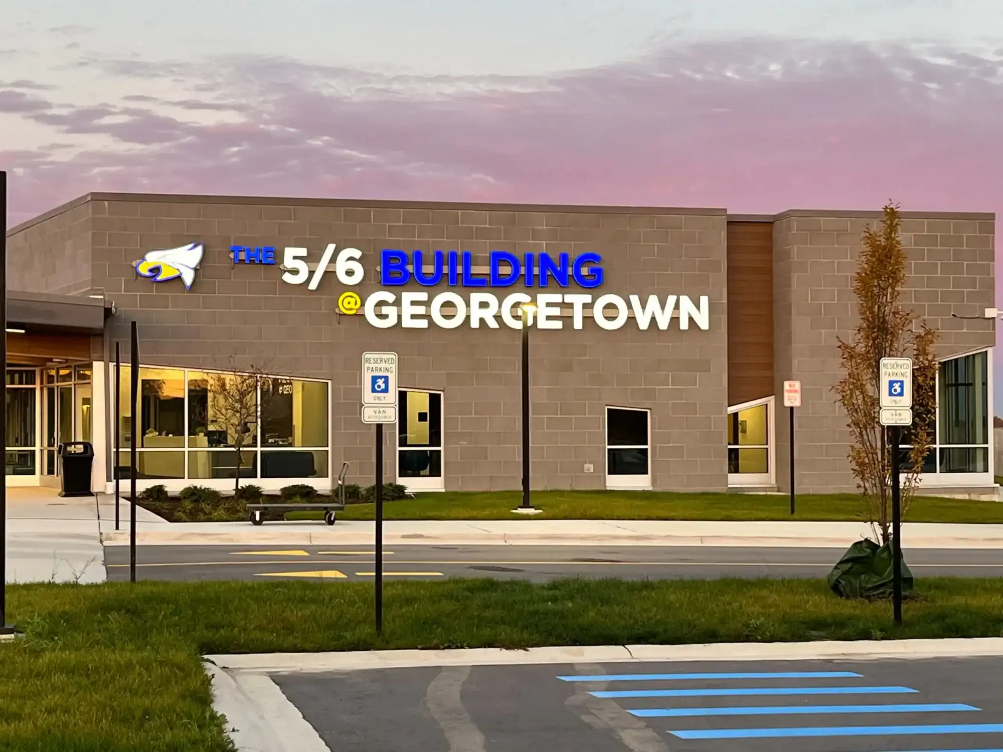 Tan Brick Commercial Building Exterior Tan-painted commercial building exterior with illuminated storefront windows, entrance doors, and manicured landscape at