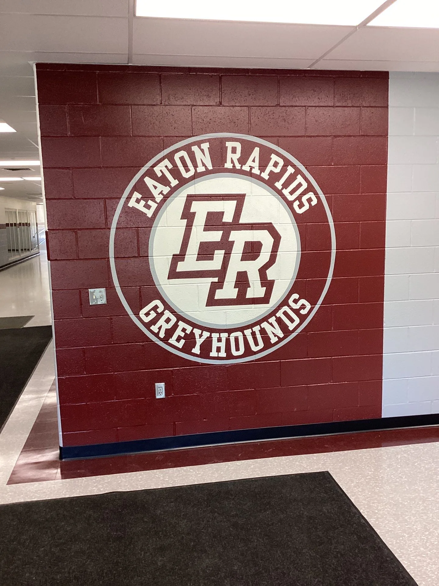 Eaton Rapids Greyhounds School Logo Mural Burgundy-painted interior wall with cream Eaton Rapids Greyhounds circular logo mural and navy base trim.