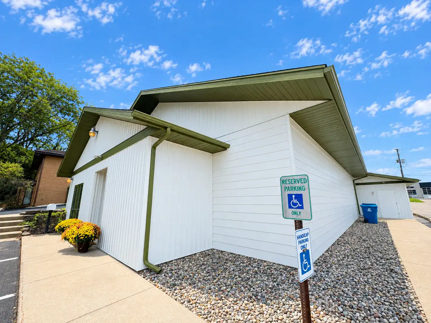 White Commercial Building Green Trim White-painted commercial building exterior with green metal trim, horizontal siding, and accessible parking area in Grand