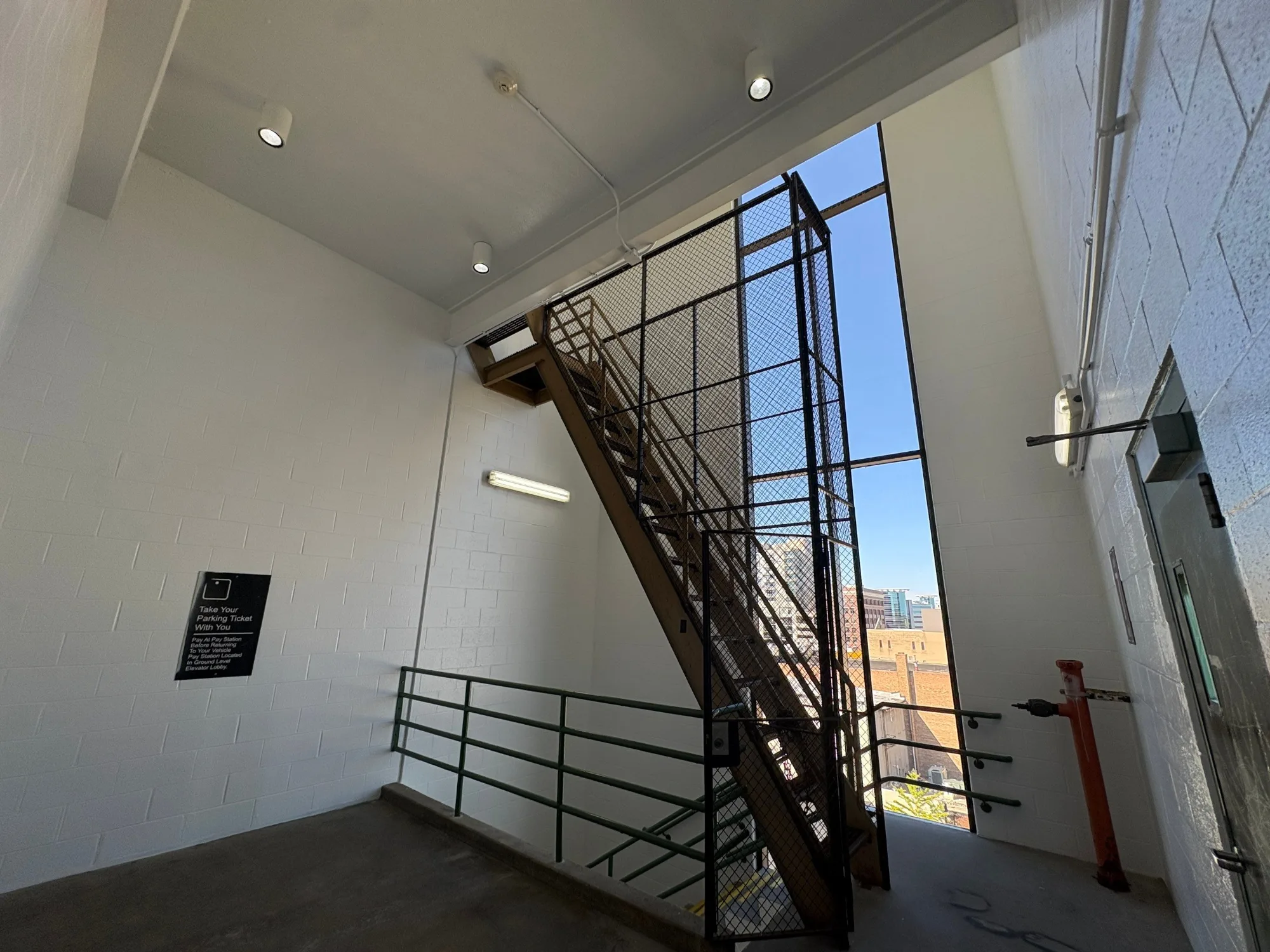 White Painted Commercial Stairwell White-painted commercial stairwell interior with black metal mesh safety gate, recessed ceiling lights, and industrial